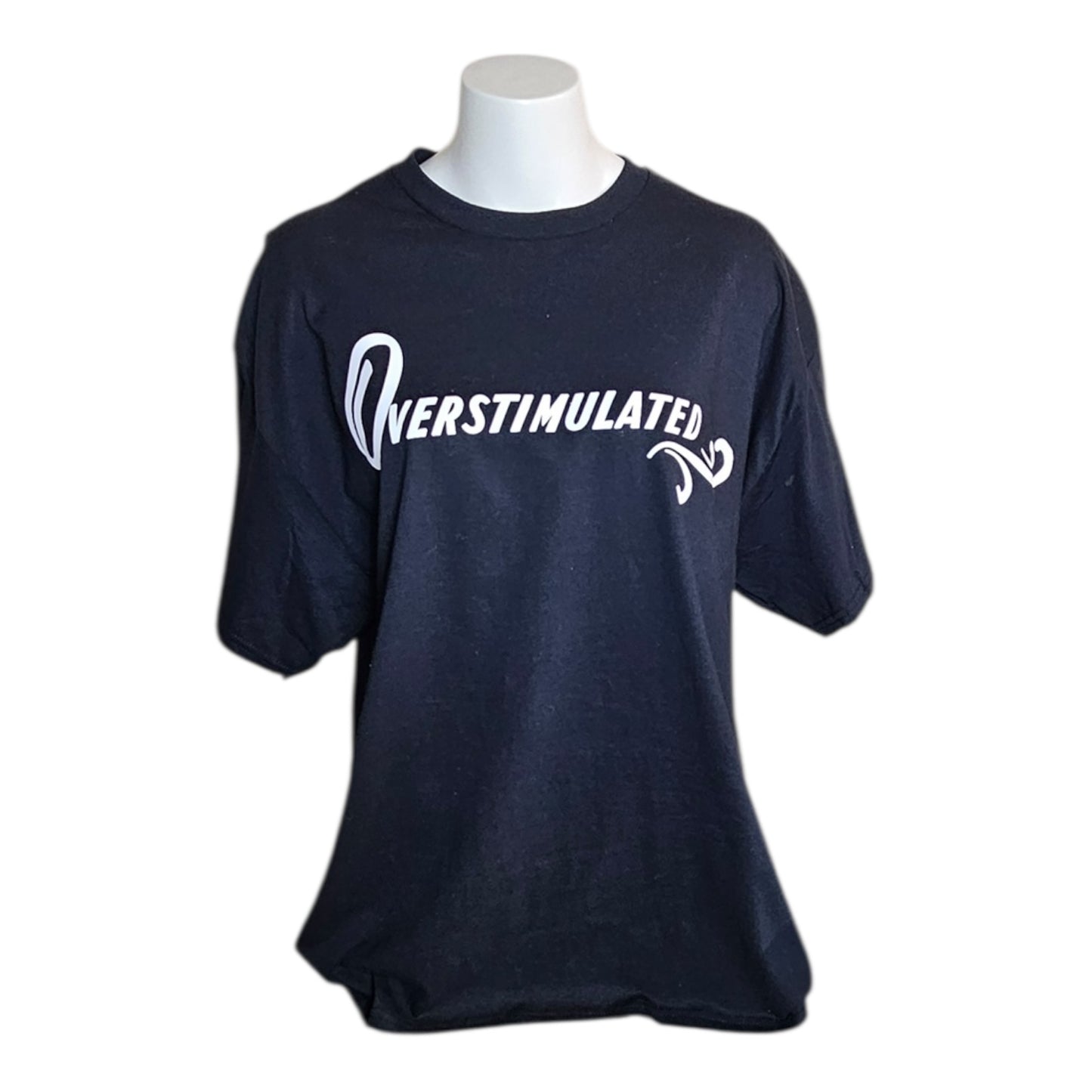 The Try My Closet Overstimulated Black Graphic Tee is shown on a white mannequin, featuring bold white OVERSTIMULATED lettering with a retro swirl design for standout graphic tee style.