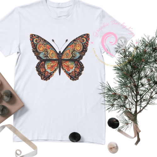 The Morphed Graphic Tee by Try My Closet is a white t-shirt featuring a bold butterfly and floral graphic. Artfully displayed with decorative items, it’s perfect for custom orders!.