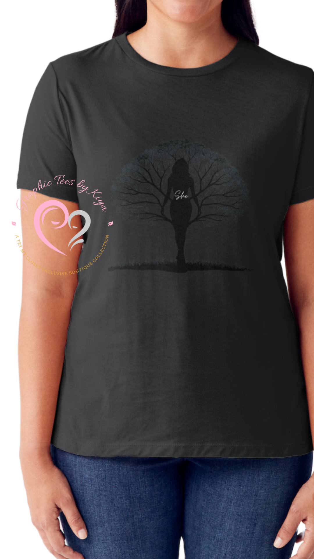 A woman wears the Try My Closet Shes Rooted in Family Graphic Tee, featuring a female silhouette, bare tree, She. Rooted in Family text, and a pink boutique logo on the lower left. Custom orders available.