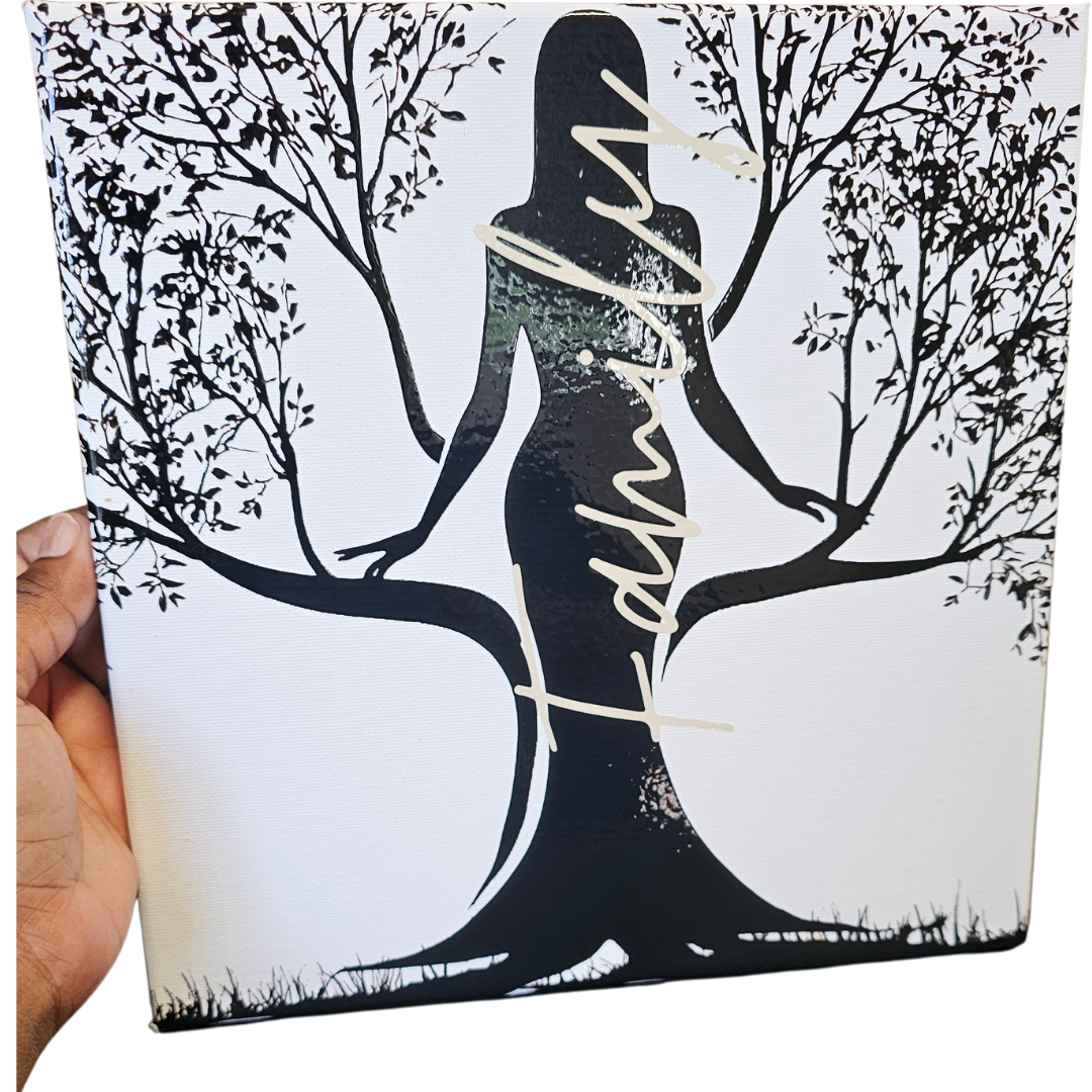 A hand displays the Try My Closet Rooted Family Canvas 10x10, featuring a womans silhouette whose dress forms a tree with branches and leaves. Family in elegant script makes this wall art perfect for your home décor.
