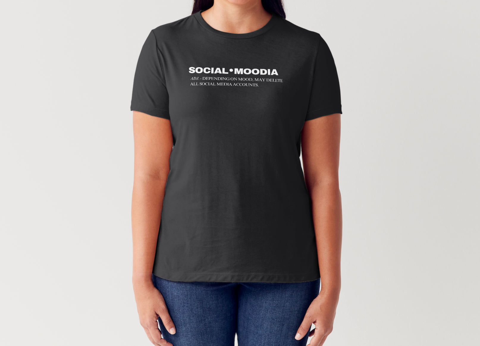 A woman wears the black Social Moodia Graphic Tee by Try My Closet with blue jeans. The shirt says: SOCIAL MOODIA—All depending on mood, may delete all social media accounts. Custom orders available.