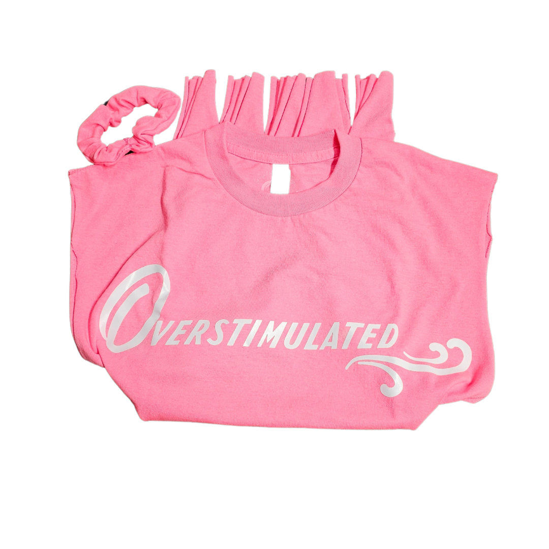 The Retro Style Overstimulated Graphic Tee in hot pink by Try My Closet, featuring white script and limited edition design, is displayed folded next to a free matching scrunchie on a crisp white background.