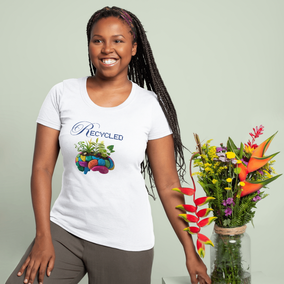 A smiling woman with braided hair wears a white “Recycled” t-shirt featuring a colorful plant graphic. She stands next to a vase filled with tropical and wildflowers against a light background.