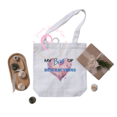The Try My Closet My Bag of Distractions Reusable Tote is a white tote with “MY Bag OF DISTRACTIONS” over a pink watercolor heart—perfect for showcasing sustainable style. Surrounded by string balls, a gift, and decorative orbs.
