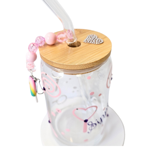 The Sippie Sippie Lollipop Candy Color Changing Glass Tumbler by Try My Closet features pink designs, a bamboo lid with a silver heart, glass straw, beaded pink charm, and handmade details—perfect for stylish sipping on any white surface.